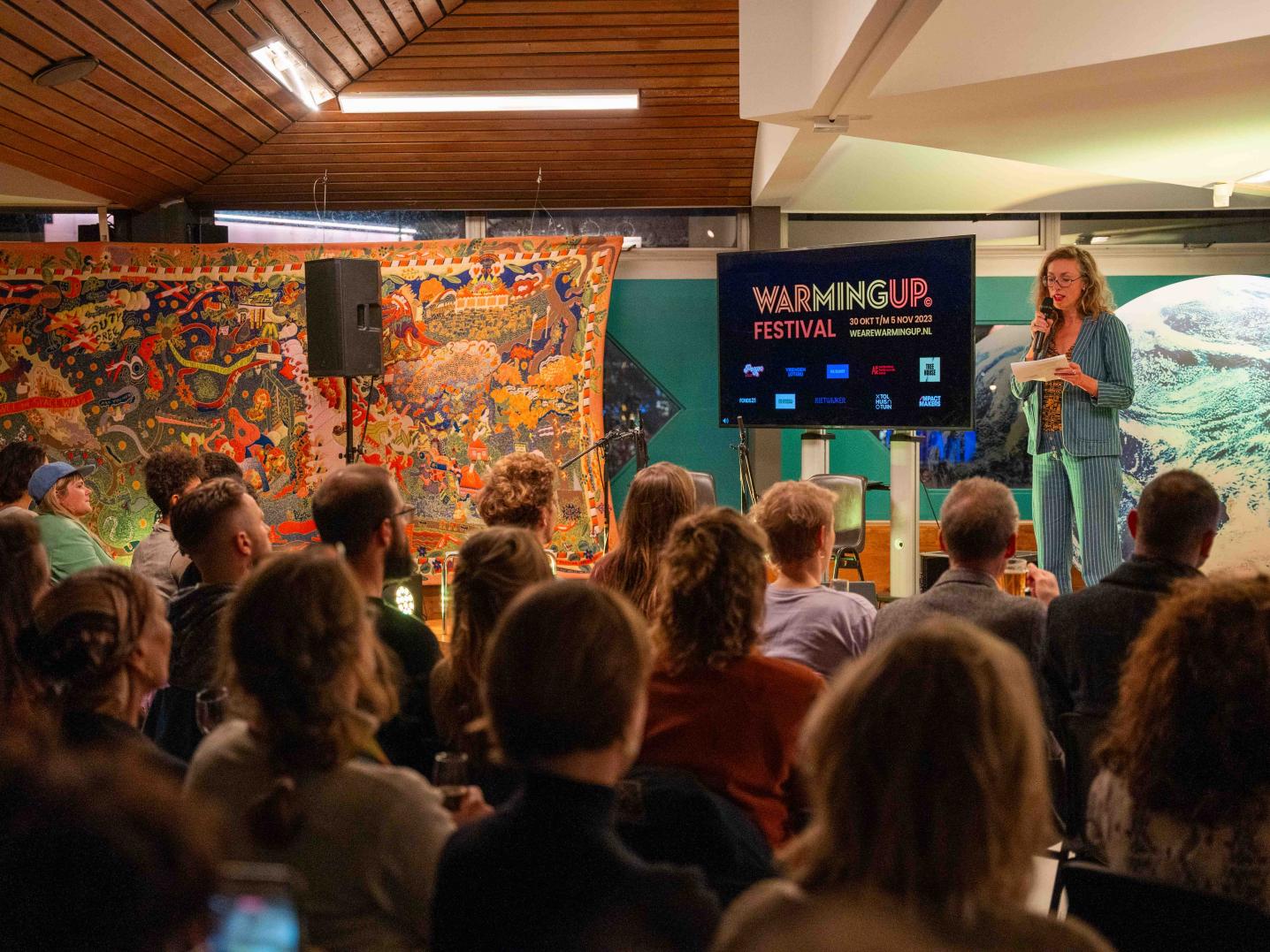 a woman talking on stage to a group of people