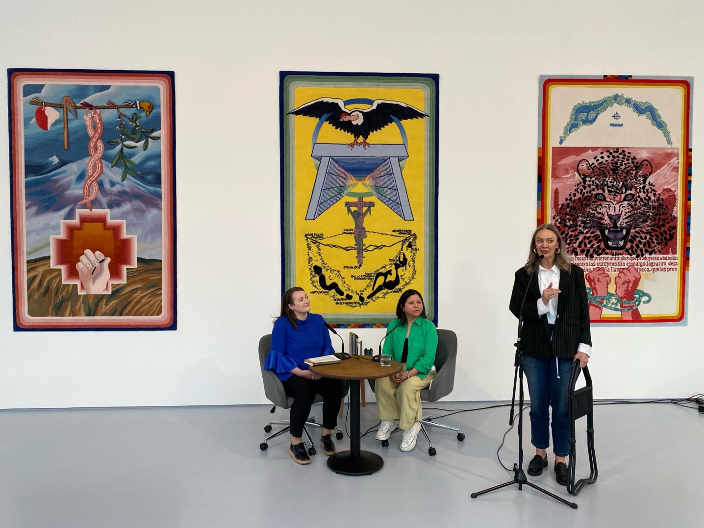 Three women standing in front of paintings at an event at Dundee Contemporary Arts in Scotland.