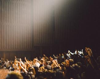 Audience members wave towards a stage.