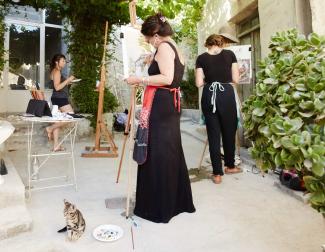 three women artists painting on easles outside an old village house in Crete, Greece