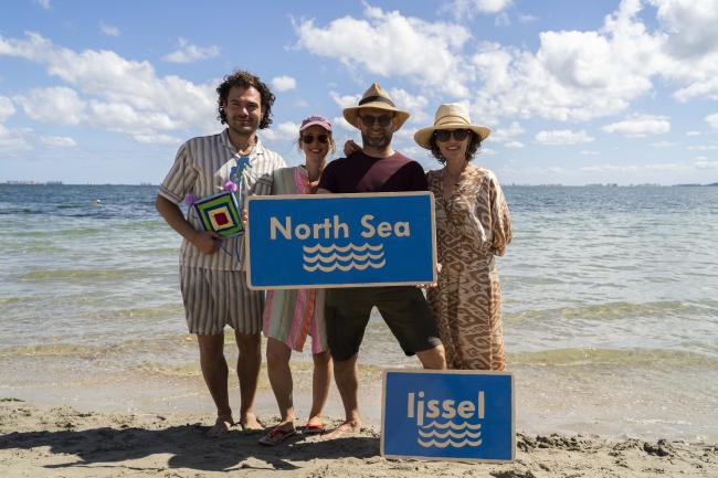 A group of people standing on a beach holding a sign saying "North Sea"