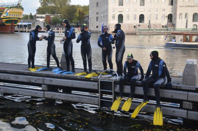 Group of people in diving suits preparing to dive.