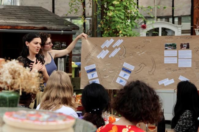 2 woman presenting in front of a small crowd.