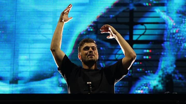 DJ Martin Garrix performing in front of a bright blue screen 